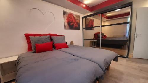 a bedroom with a large bed with red pillows at Le duo virtonnais - appartement 4 personnes au coeur de la gaume in Virton