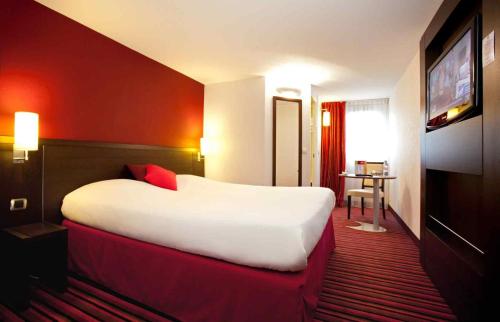 a hotel room with a large bed and a television at ibis Styles Belfort Centre in Belfort