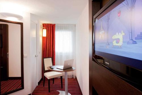 a room with a laptop on a table and a tv at ibis Styles Belfort Centre in Belfort