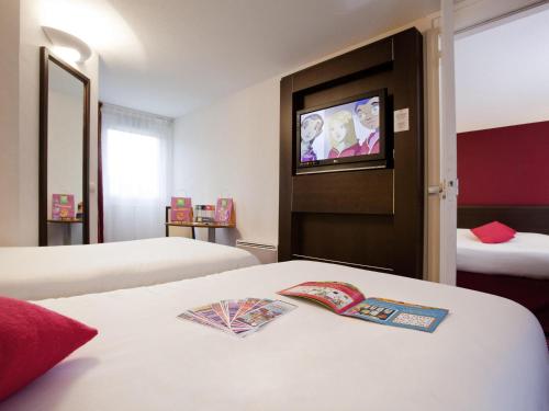 a hotel room with two beds and a flat screen tv at ibis Styles Belfort Centre in Belfort