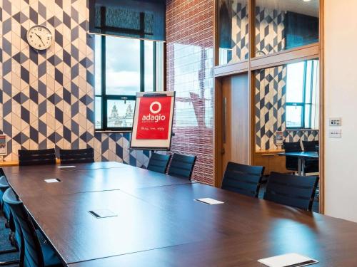 a large table in a room with chairs and a clock at Aparthotel Adagio Liverpool City Centre in Liverpool