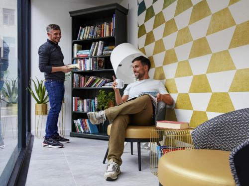 a man sitting in a chair in a book shelf at Aparthotel Adagio Liverpool City Centre in Liverpool