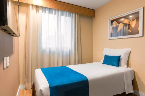 a hotel room with a bed with a blue pillow at Wyndham Sao Paulo Ibirapuera Convention Plaza in Sao Paulo