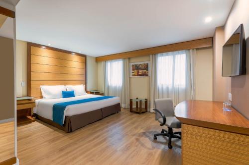 a hotel room with a bed and a desk at Wyndham Sao Paulo Ibirapuera Convention Plaza in Sao Paulo