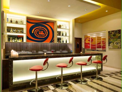 a bar with red stools in a restaurant at ibis Nashik - An Accor Brand in Nashik
