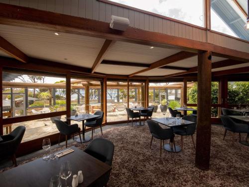 a restaurant with tables and chairs and windows at Mercure Kangaroo Island Lodge in American River