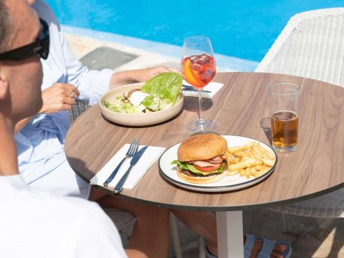 a man sitting at a table with a sandwich and french fries at Mercure Kangaroo Island Lodge in American River