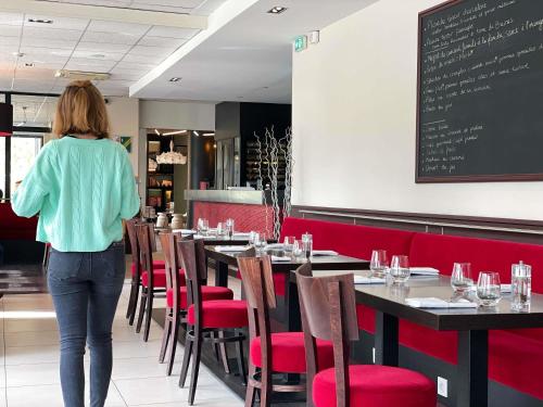 a woman walking through a restaurant with tables and chairs at ibis Styles Bordeaux Centre Mériadeck in Bordeaux
