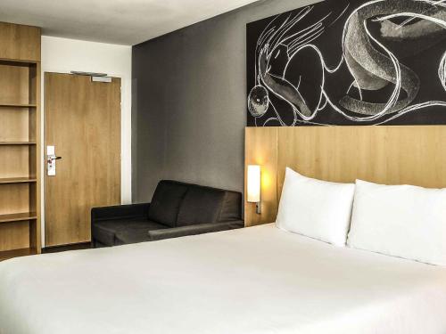 a hotel room with a bed and a chair at Ibis Saint-Genis-Pouilly Genève in Saint-Genis-Pouilly