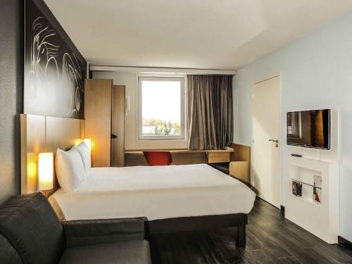 a hotel room with a large bed and a couch at Ibis Saint-Genis-Pouilly Genève in Saint-Genis-Pouilly