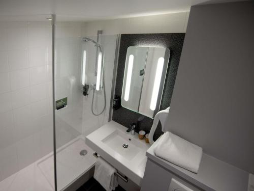 a bathroom with a shower and a sink and a mirror at Ibis Saint-Genis-Pouilly Genève in Saint-Genis-Pouilly