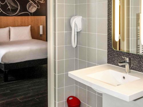 a bathroom with a sink and a bedroom with a bed at Ibis Saint-Genis-Pouilly Genève in Saint-Genis-Pouilly