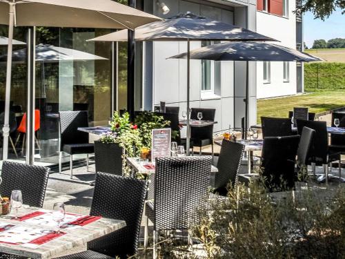 a restaurant with tables and chairs with umbrellas at Ibis Saint-Genis-Pouilly Genève in Saint-Genis-Pouilly