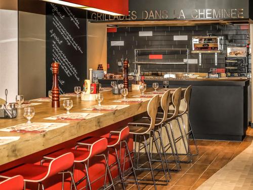 a long bar with chairs in a restaurant at Ibis Saint-Genis-Pouilly Genève in Saint-Genis-Pouilly