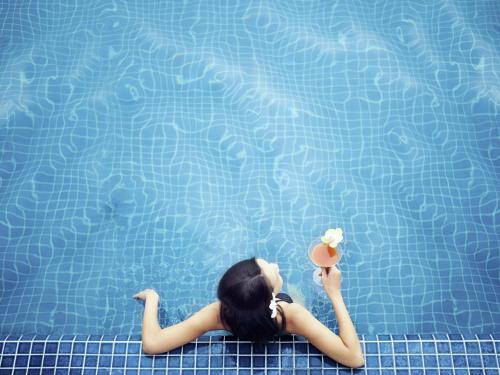 a woman laying in a pool holding a ball and flowers at Ibis Saint-Genis-Pouilly Genève in Saint-Genis-Pouilly