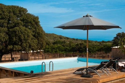 - une piscine avec un parasol, des chaises et une table dans l'établissement Les Chalets de Tesa, à Occhiatana