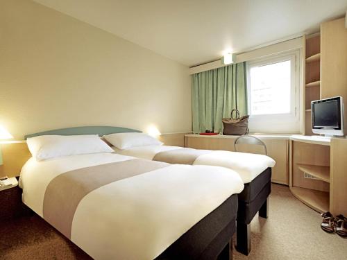 a hotel room with two beds and a television at ibis Loriol Le Pouzin in Le Pouzin