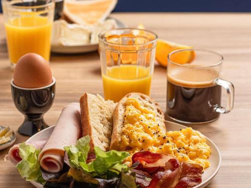 a plate of breakfast food on a table with orange juice at ibis Loriol Le Pouzin in Le Pouzin
