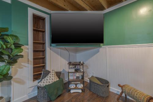 a living room with a flat screen tv on the wall at Game On! 4br Near Acadia Wfire Pit, Games & More in Ellsworth