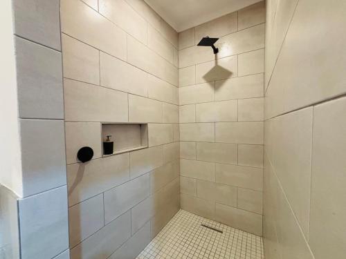 a bathroom with a shower with white tiles at East Park Inn in Polokwane