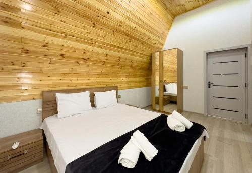 a bedroom with a bed with two towels on it at Qafqaz Riverside Chalet in Gabala