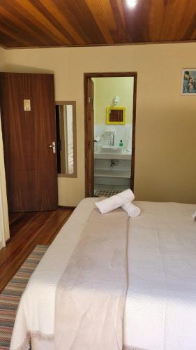 a large white bed in a room with a bathroom at Suítes La Reserve in Campos do Jordão