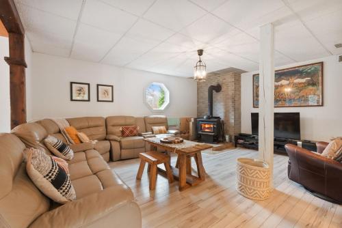 a living room with a couch and a fireplace at L'Évasion - 4CH - Piscine - Spa et Salle de jeux in Saint Zenon