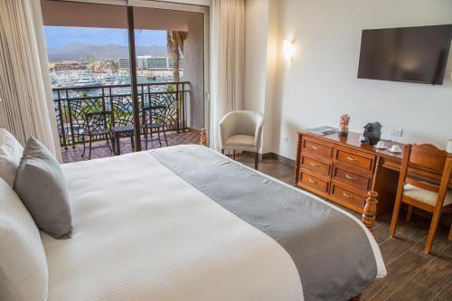 a hotel room with a bed, chair and a tv at Sandos Finisterra All Inclusive in Cabo San Lucas