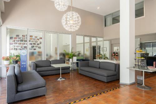 a living room with couches and a chandelier at Ratchadamnoen Residence in Bangkok