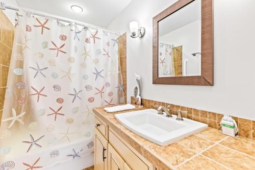 ein Badezimmer mit Waschbecken und Duschvorhang in der Unterkunft Seagrove Villa 11C - Oceanfront View! Center of Resort! in Isle of Palms