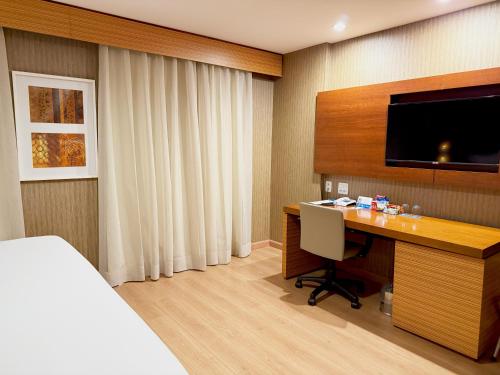 a hotel room with a desk and a television at Wyndham Sao Paulo Ibirapuera Convention Plaza in Sao Paulo