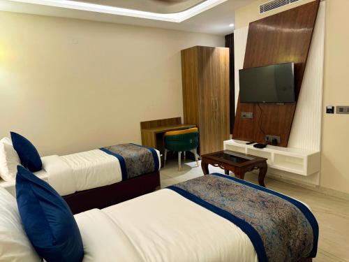 a hotel room with two beds and a flat screen tv at RC Dream Palace in Greater Noida