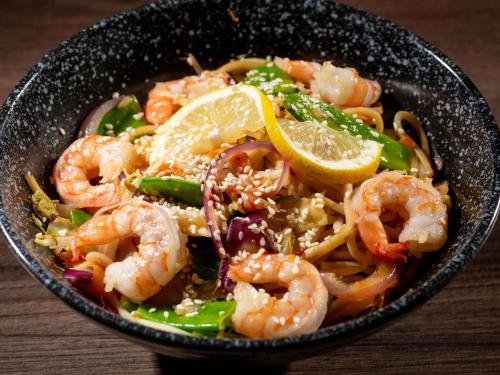 a bowl of shrimp pasta with a lemon slice at ibis Lyon Est Chaponnay in Chaponnay