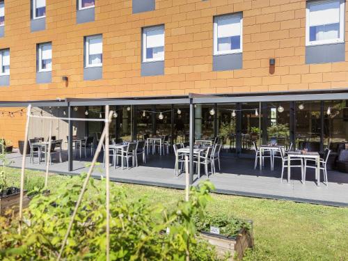 a restaurant with tables and chairs outside of a building at ibis Lyon Est Chaponnay in Chaponnay