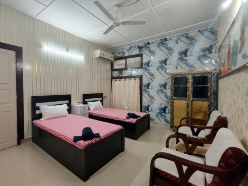 a room with two beds and a chair in it at Aira homestay in Guwahati