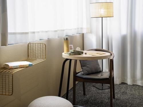 a table and a chair and a lamp in a room at ibis Styles Rennes St. Gregoire in Saint-Grégoire
