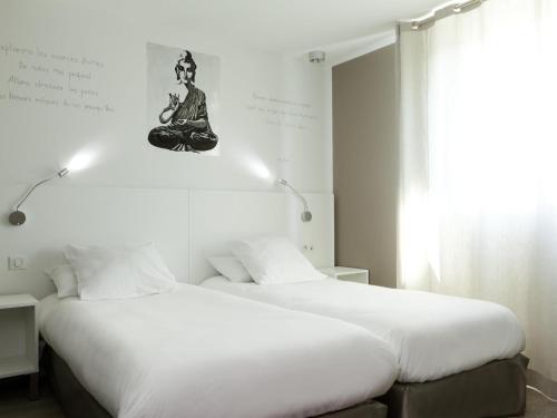 two beds sitting next to each other in a bedroom at ibis Styles Rennes St. Gregoire in Saint-Grégoire