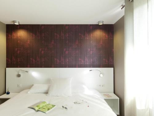 a bedroom with a white bed with a red wall at ibis Styles Rennes St. Gregoire in Saint-Grégoire