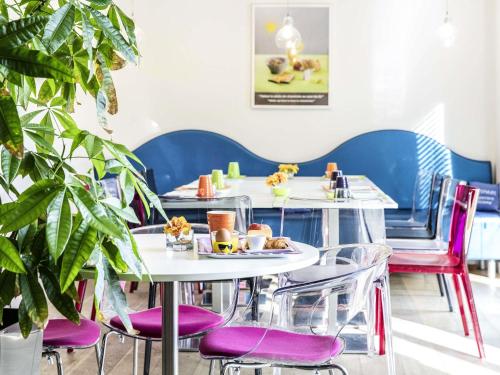 a restaurant with purple chairs and tables with food on them at ibis Styles Rennes St. Gregoire in Saint-Grégoire