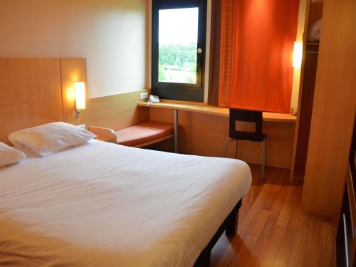 a hotel room with a bed and a window at Hôtel ibis Guingamp Cœur de Bretagne in Ploumagoar
