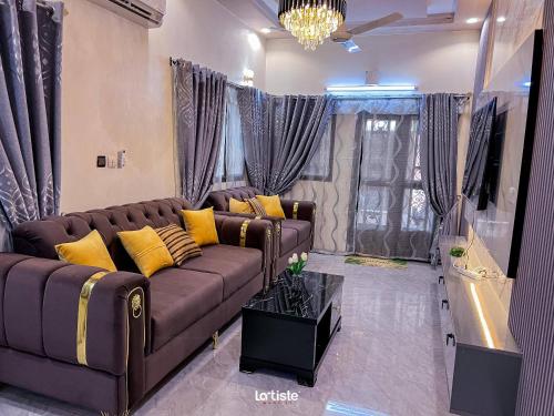 un soggiorno con divano marrone e cuscini gialli di Magnifique Mini-Villa Ouagadougou! a Ouagadougou