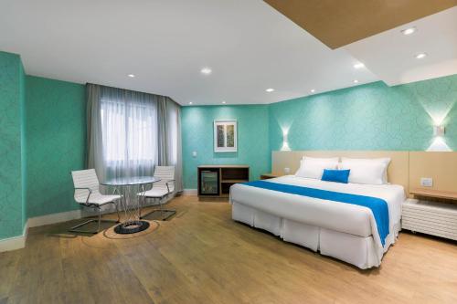 a bedroom with a large bed and a table at Wyndham Sao Paulo Ibirapuera Convention Plaza in Sao Paulo