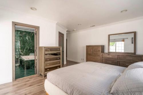 a bedroom with a bed and a mirror and a sink at Modern Encino Retreat with pool, lush yard and comfort in Encino