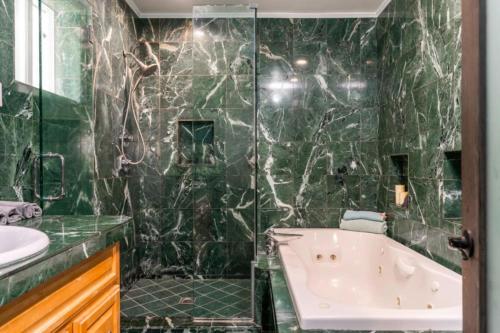 a bathroom with a shower and a tub and a sink at Modern Encino Retreat with pool, lush yard and comfort in Encino