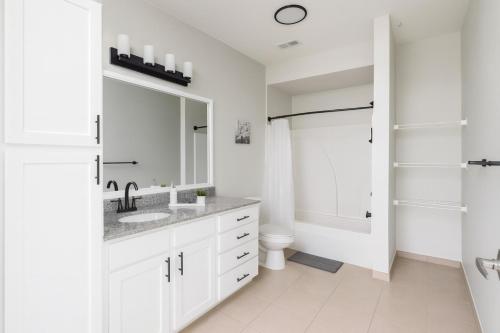 a white bathroom with a sink and a mirror at Spacious 2BR 2BA Condo Across from UAB in Homewood