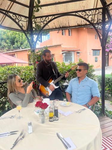 a group of people sitting around a table with a guitar at Rukka Lodge in Tumbaco