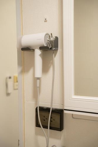 a white blow dryer is plugged into a wall at Ratchadamnoen Residence in Bangkok