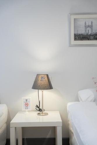 a white table with a lamp on it next to a bed at Ratchadamnoen Residence in Bangkok