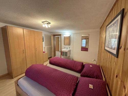 a bedroom with two beds with purple cushions in it at Chalet Medi in Zermatt