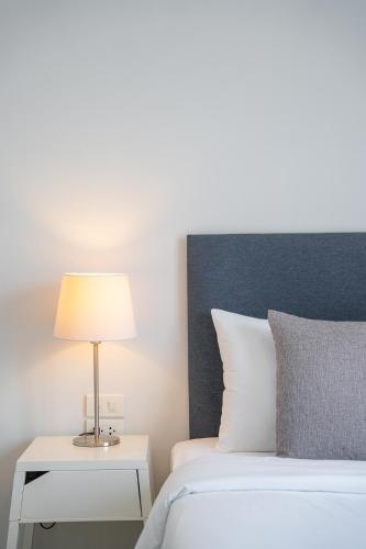 a bedroom with a bed with a lamp on a side table at Ratchadamnoen Residence in Bangkok